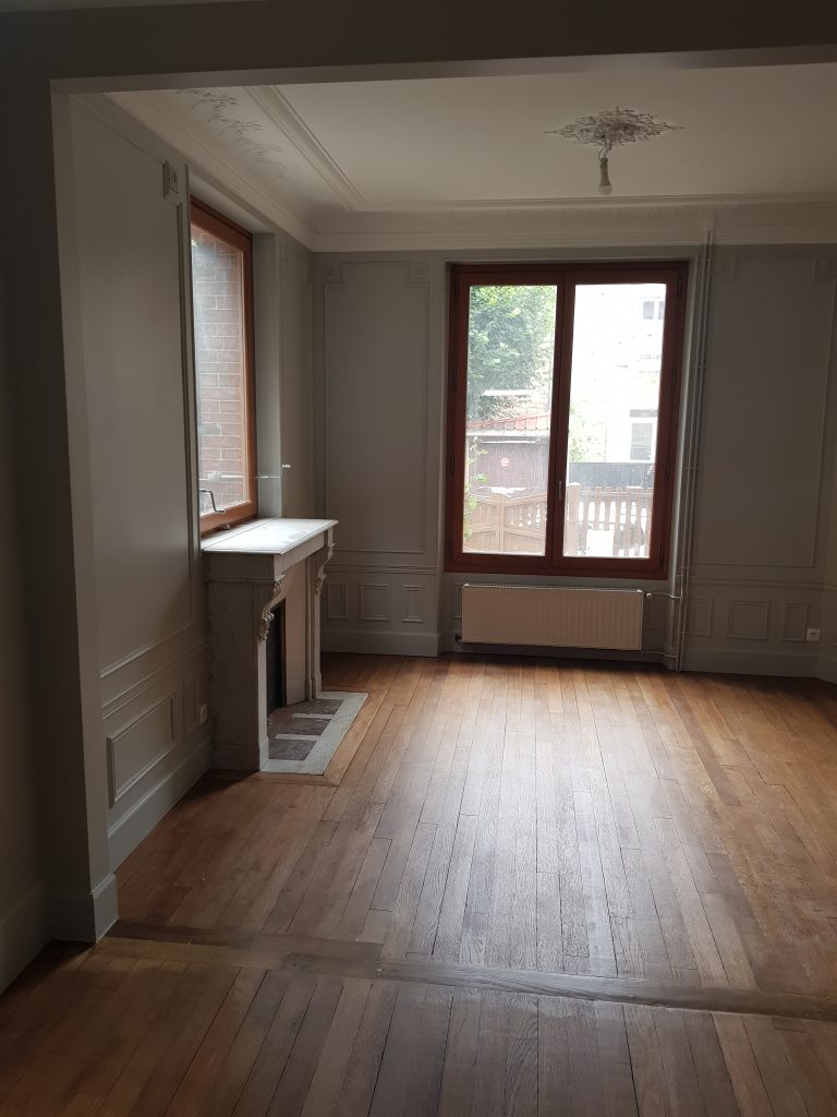 Pièce rénovée à Paris avec peinture grise, boiseries murales et parquet ancien restauré suite à un sinistre